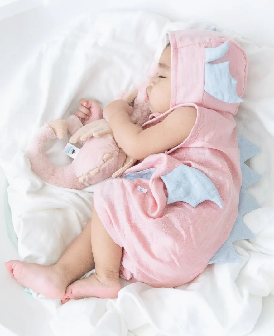 Baby sleeping in a pink dragon romper